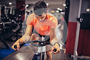 Man biking in the gym, exercising legs doing cardio workout cycling bikes