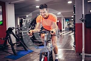 Man biking in the gym, exercising legs doing cardio workout cycling bikes