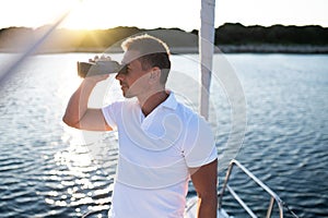 Man with binocular standing on a yacht deck