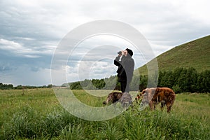 A man with binoculars looking into the distance. With man two dogs in field