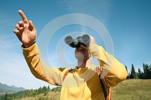 Man with binoculars in mountains on sunny day