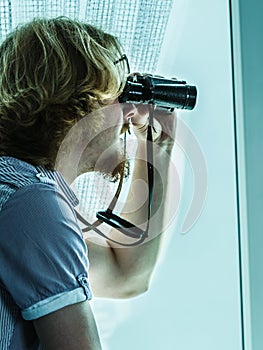 Man with binoculars spying on neighbors