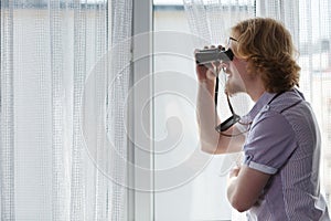 Man with binoculars spying on neighbors