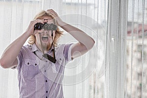 Man with binoculars spying on neighbors