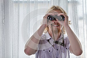 Man with binoculars spying on neighbors