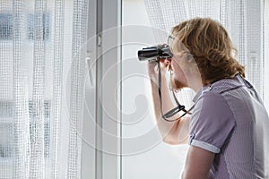 Man with binoculars spying on neighbors