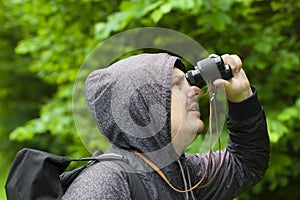 Man with binoculars watching birds in the park