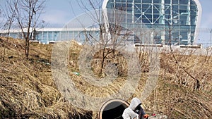 Man in bio-hazard suit and gas mask checks the pollution of the water outside