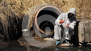 Man in bio-hazard suit and gas mask checks the pollution of the water outside
