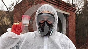 Man in bio-hazard suit and gas mask looks straight into the camera