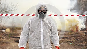 Man in bio-hazard suit and gas walks to the polluted zone covered with smoke