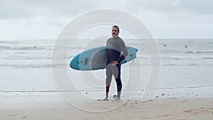 Man with bionic leg standing on beach with surfboard under arm