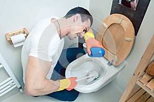 Man is a bit disgusted cleaning the toilet