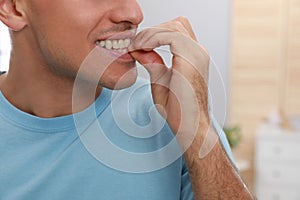 Man biting his nails indoors, closeup. Bad habit