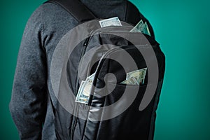 Man with a black backpack from which protrude dollars photo