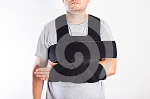 A man in a black bandage supporting the shoulder joint after ligament damage and bruise. Dislocation of the shoulder