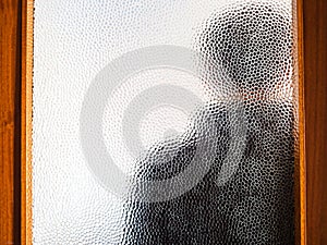 Man in black behind closed door through glass