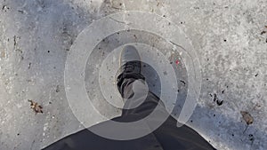 Man in black boots slides down an icy path at clear frosty sunny weather, boots with laces, trousers of black color, the