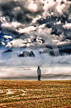 Man in black clothes standing on horizon under datk cloud