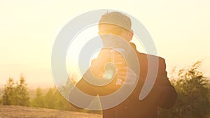 man in black glasses and black jacket sings song into shiny vintage retro microphone in nature against backdrop of