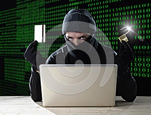 Man in black holding credit card and lock using computer laptop for criminal activity hacking bank account password