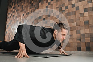 A man in black kimano practicing qigong energy exercises indoors