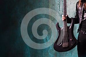 Man in black leather holding a guitar. Rocker and metalhead, youth style, music. Textured background, place for text