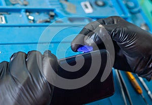 Man with black rubber glove repairing mobile phone