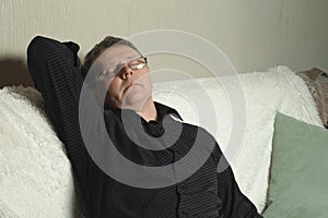 A man in a black shirt dozed off on the couch