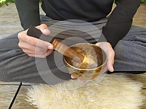 A man with a black shirt playing a tibetan bowl