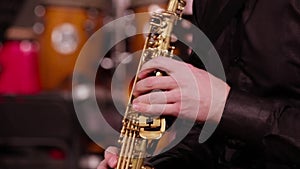 A man in a black shirt plays jazz music. Close-up of the hands of a saxophonist on a soprano saxophone.