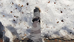 a man in black shoes breaks last snow in the park at first sunny days