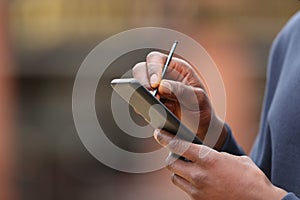 Man with black skin hands using pen on phone