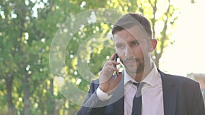Man in black speaking on phone then lowering phone and looking seriously