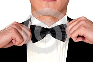 Man in a black suit adjusts his bow tie close-up face