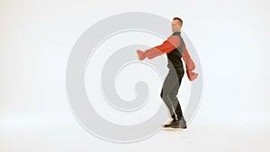 A man in a black suit and a red shirt is dancing on a white background.