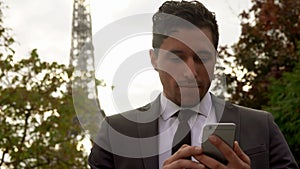 Man in black suit sends message on a cell phone