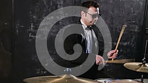 Man in black suit and sunglasses plays on drum. Rock cover band performing on stage with drummer