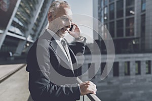 Man in a black suit talking on the phone.