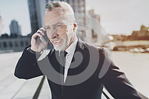 Man in a black suit talking on the phone.