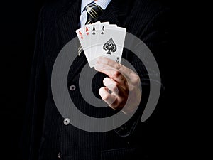 A man in a black suit and a tie holds 4 aces in his hand