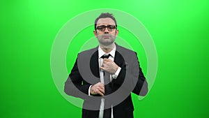 Man In Black Suit Tying A Tie On A Green Background