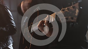 man in a black sweatshirt plays the acoustic guitar