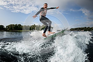 Man black swimsuit rides a wave off the coast with his surfboard.