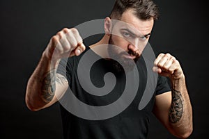 Man in black t-shirt standing in fighting stance on black background