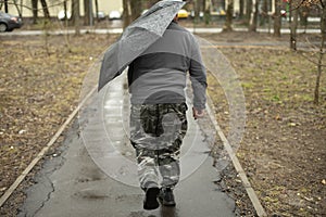 Man with black umbrella. Man walks down street in rain