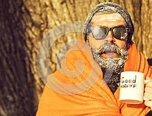 Man in blanket with cup on winter day on natural background