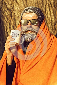 Man in blanket with cup on winter day outdoors on natural background