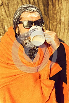 Man in blanket with cup on winter day outdoors on natural background