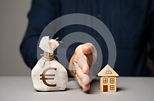 A man blocking a house from a euro money bag. Rejection of the deal.